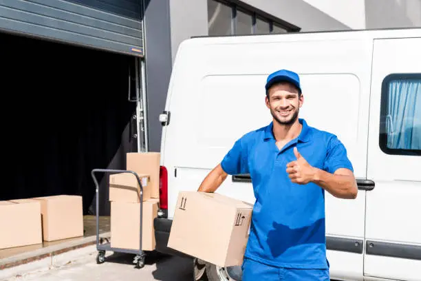 smiling delivery man with box showing thumb up