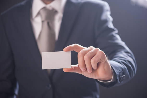 istock man's hand showing business card isolated on dark background 856295676