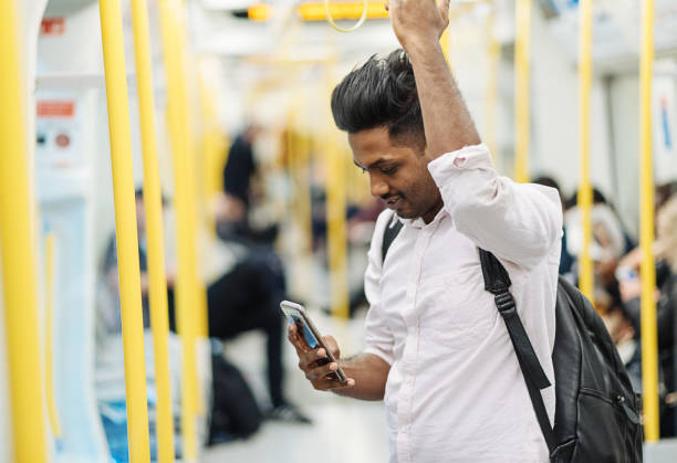 tren de cercanías con hombre indio que está utilizando el teléfono inteligente mientras viaja - trabajador emigrante fotografías e imágenes de stock
