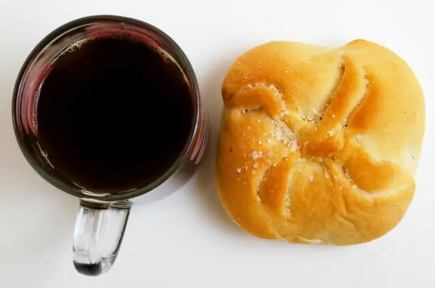 Black coffee and bun on a light background.