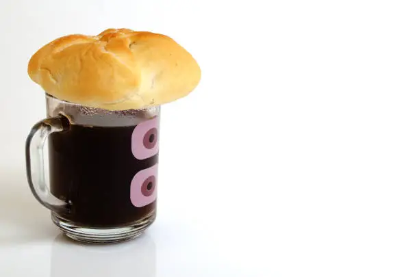 Black coffee and bun on a light background.