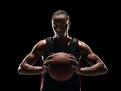 The african man basketball player standing with ball on black studio background