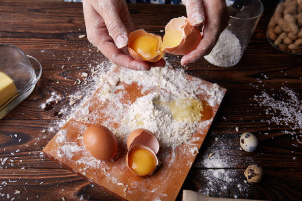 istock Top view of hands holding a cracked egg with yolk on a table background. Baking and dough making. 856318728