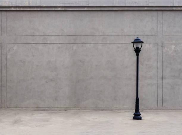 The lamp on the footpath and the wall in the dim atmosphere.