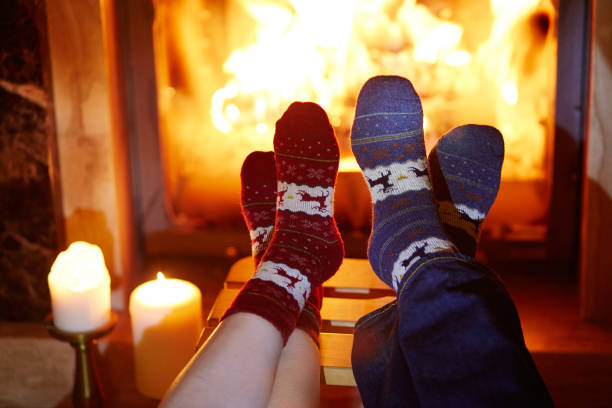 istock Man and woman in warm socks near fireplace 856335532