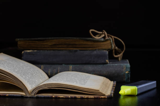 istock Old book lying on a black countertop and office marker. black background 856338750