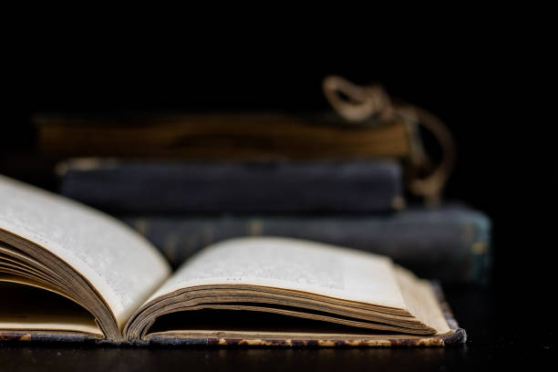 istock An old book lying on a black table. In the background a pile of old chunks. Black table, black background. 856338846