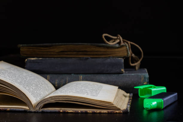 istock Old book lying on a black countertop and office marker. black background 856339138