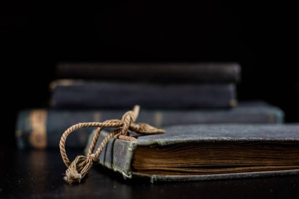 istock An old book lying on a black table. In the background a pile of old chunks. Black table, black background. 856339142