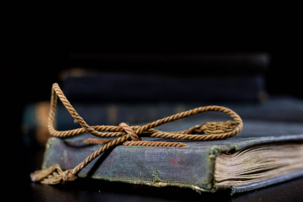 istock An old book lying on a black table. In the background a pile of old chunks. Black table, black background. 856341480