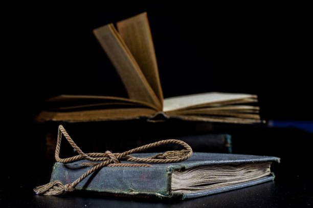 istock An old book lying on a black table. In the background a pile of old chunks. Black table, black background. 856342012