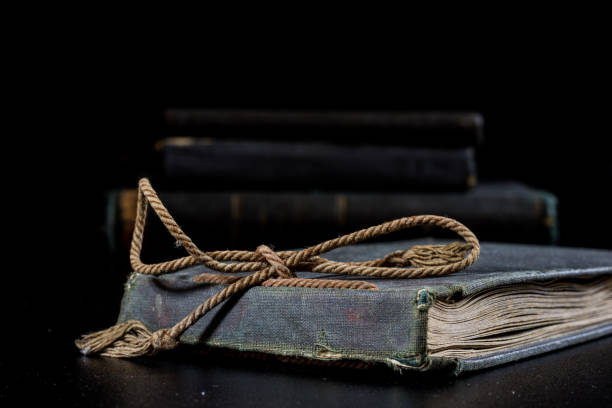istock An old book lying on a black table. In the background a pile of old chunks. Black table, black background. 856342056