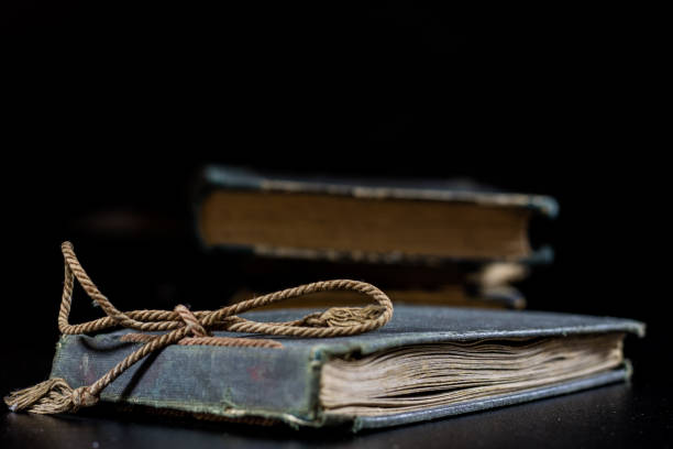 istock An old book lying on a black table. In the background a pile of old chunks. Black table, black background. 856342298