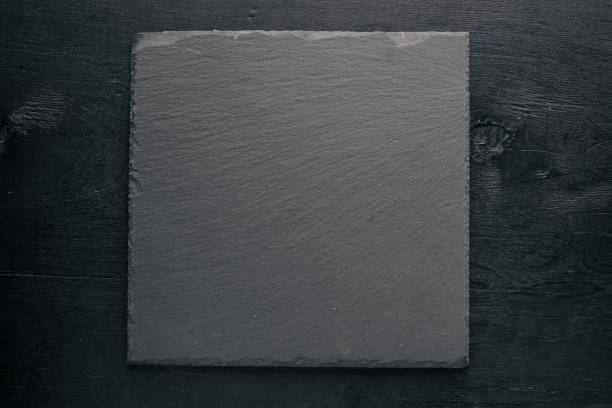 istock Black stone board. On a wooden background. Top review. Free space. 856345078