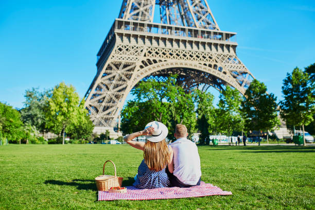 paar mit picknick in der nähe des eiffelturms in paris, frankreich - paris france eiffel tower love kissing stock-fotos und bilder