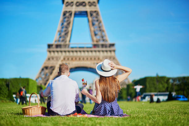 paar mit picknick in der nähe des eiffelturms in paris, frankreich - paris france eiffel tower love kissing stock-fotos und bilder