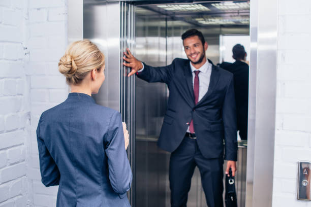 istock businessman holding elevator door for woman 856362968