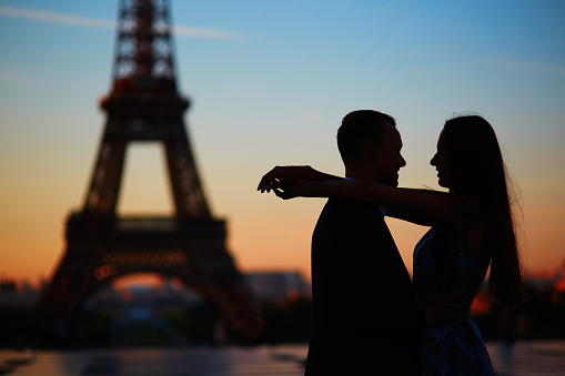Silhouettes of couple at sunrise or sunset near Eiffel tower