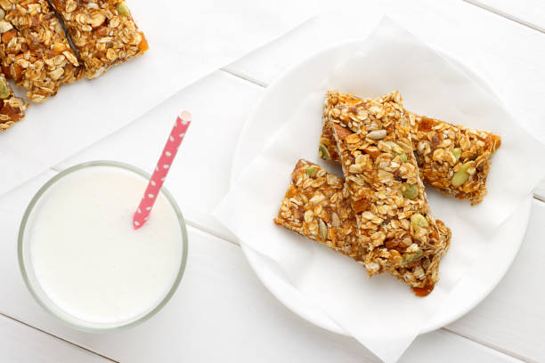 Healthy breakfast with granola bars and milk on white wooden table. stock photo