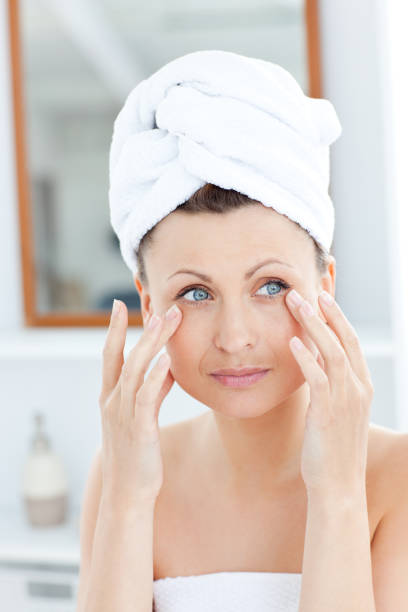 istock Attractive young woman with a towel putting cream on her face 856372304