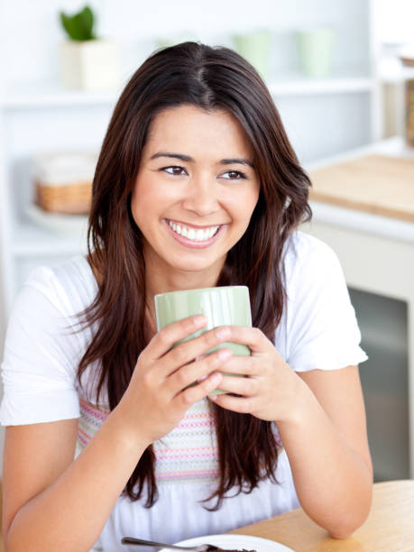 istock Beautiful woman holding a cup sitting in the kitchen 856382924