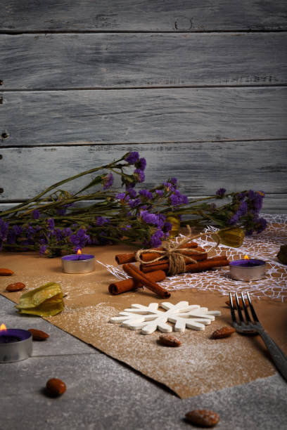 istock A fancy Christmas composition. Purple flowers, candles, white snowflake, cinnamon, and a fork on a table background. 856383084