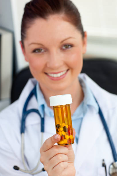 istock Delighted female doctor holding pills into the camera 856385448