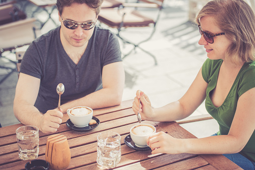 Young couple of tourists examining a map and having breakfast in a cafe