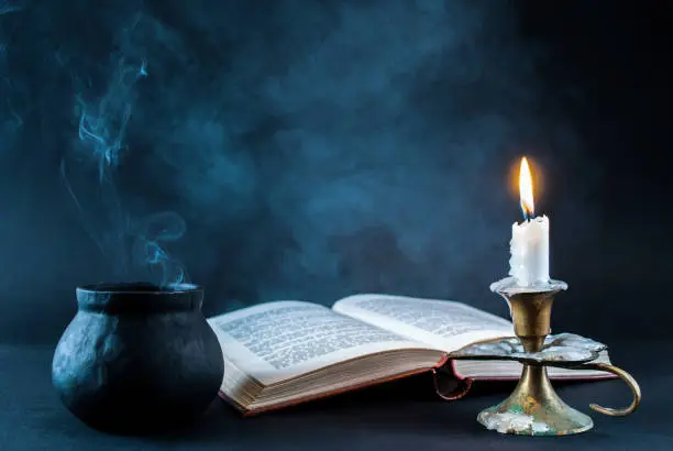 Photo of Candle in candlestick burning and old wooden box and on dark and smoked background