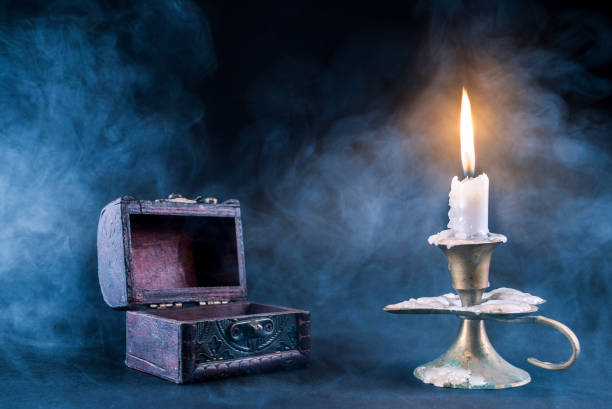 istock Candle in candlestick burning and smoky pot and old open book on dark and smoked background 856400428