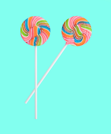 Rainbow lollipop swirl on stick isolated on sweet pastel color background.