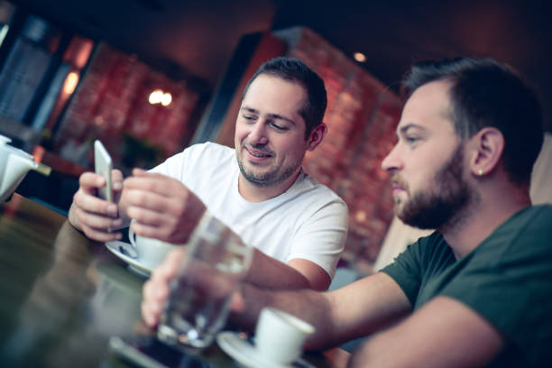 istock Two Laughing Friends looking at Smartphones In a Cafe Restaurant 856400906