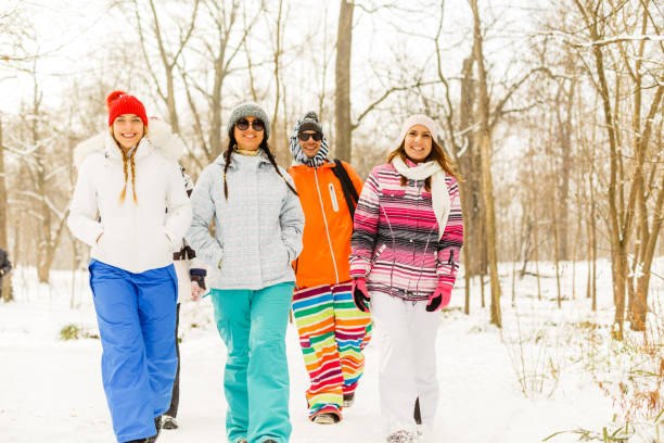 Friends walking through snowy forest Group of young friends walking through snowy forest. snowboarding snowboard women snow stock pictures, royalty-free photos & images