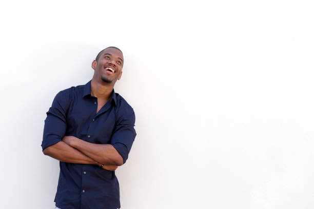 istock young black man laughing with arms crossed against white wall 856403584