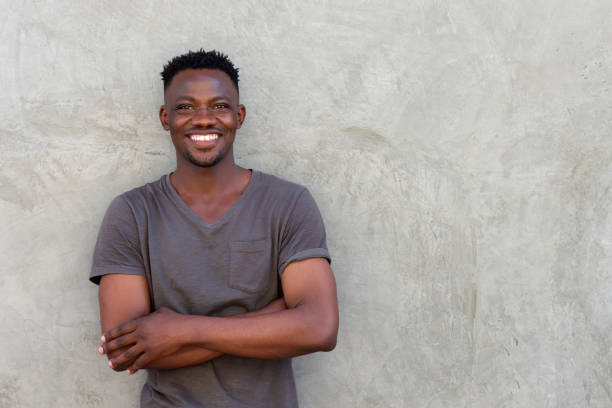 istock happy african man smiling with arms crossed by wall 856403868