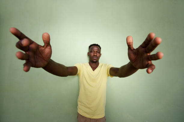 istock african man with his arms outstretched standing against green wall 856404044