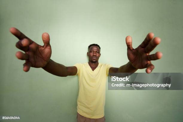 African Man With His Arms Outstretched Standing Against Green Wall Stock Photo - Download Image Now