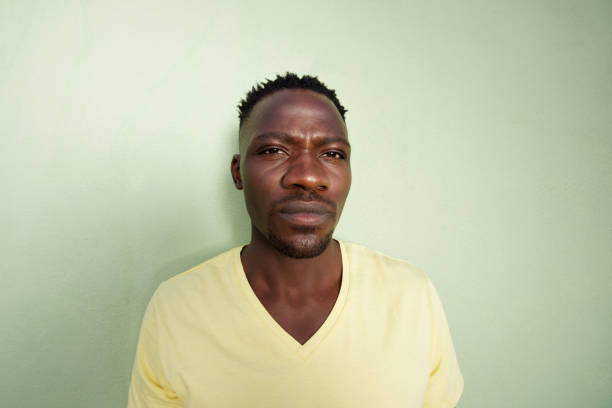 istock young african man standing against green wall 856404348