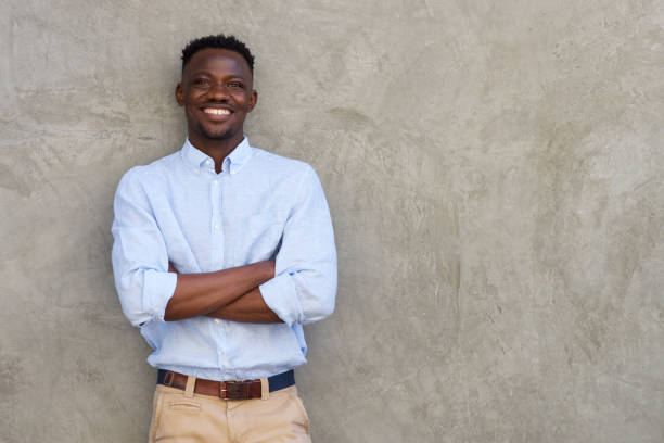 istock handsome young african man smiling with arms crossed by wall 856406922