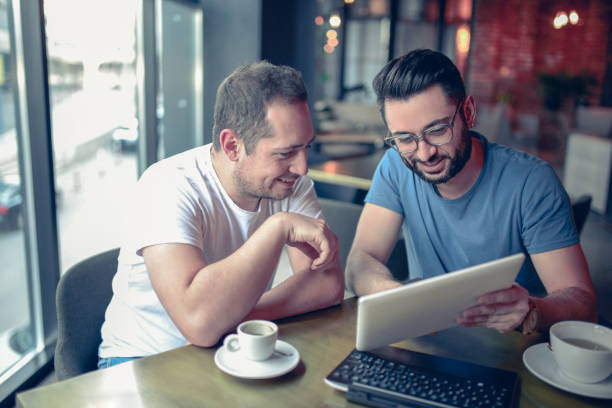 istock Two Smiling Freelancers Drinking Coffee and Working In Cafe Restaurant 856407142