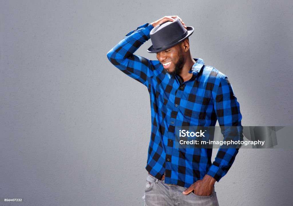 happy handsome man laughing with hand to hat Portrait of happy handsome man laughing with hand to hat African-American Ethnicity Stock Photo