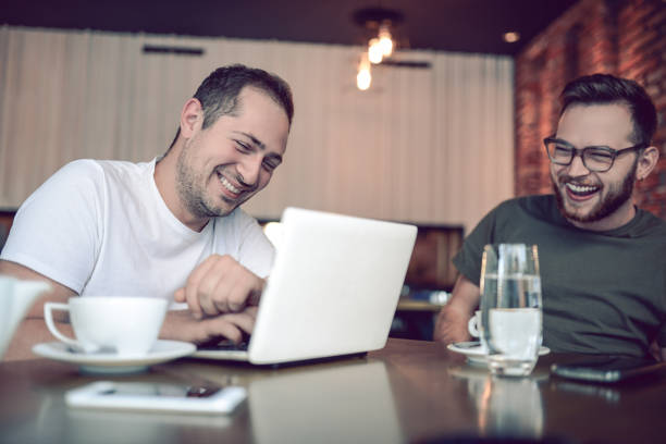 istock Two Smiling  Male Freelancers Drinking Coffee and Working In Cafe Restaurant 856407348