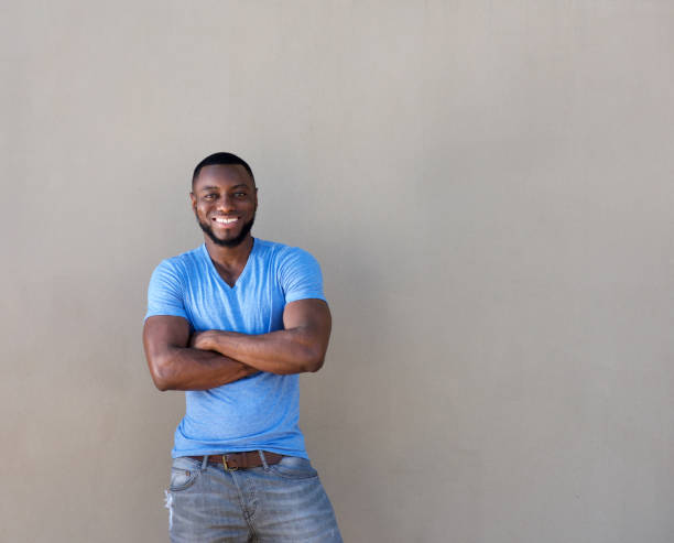 istock attractive black man with beard smiling with arms crossed 856407394