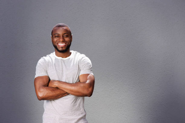 istock smiling man  standing with arms crossed against gray background 856407522