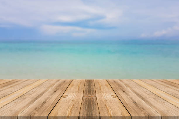 istock Wooden board empty table top blur sea & sky background. Perspective brown wood table beach background - can be used mock up for montage products display or design key visual layout. summer concepts. 856410654