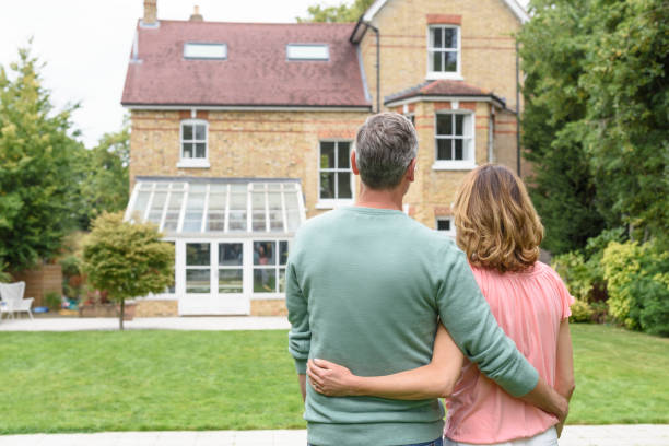 istock Mature couple with arms around each other looking at house 856410962