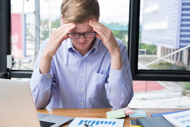 istock tired businessman with hand on forehead at office. frustrated man with headache at workplace. exhausted startup business owner in depression after long work. overwork, stress, fatigue concept 856411122
