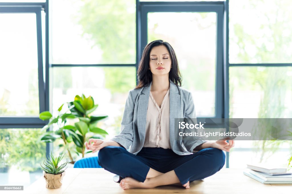 businesswoman meditating at workplace relaxed businesswoman with eyes closed meditating at workplace in office Women Stock Photo