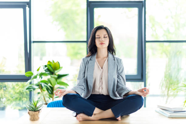 businesswoman meditating at workplace relaxed businesswoman with eyes closed meditating at workplace in office cross legged photos stock pictures, royalty-free photos & images