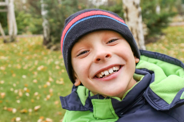 istock A funny  toddler boy in a warm jacket and hat laughing at garden 856418162